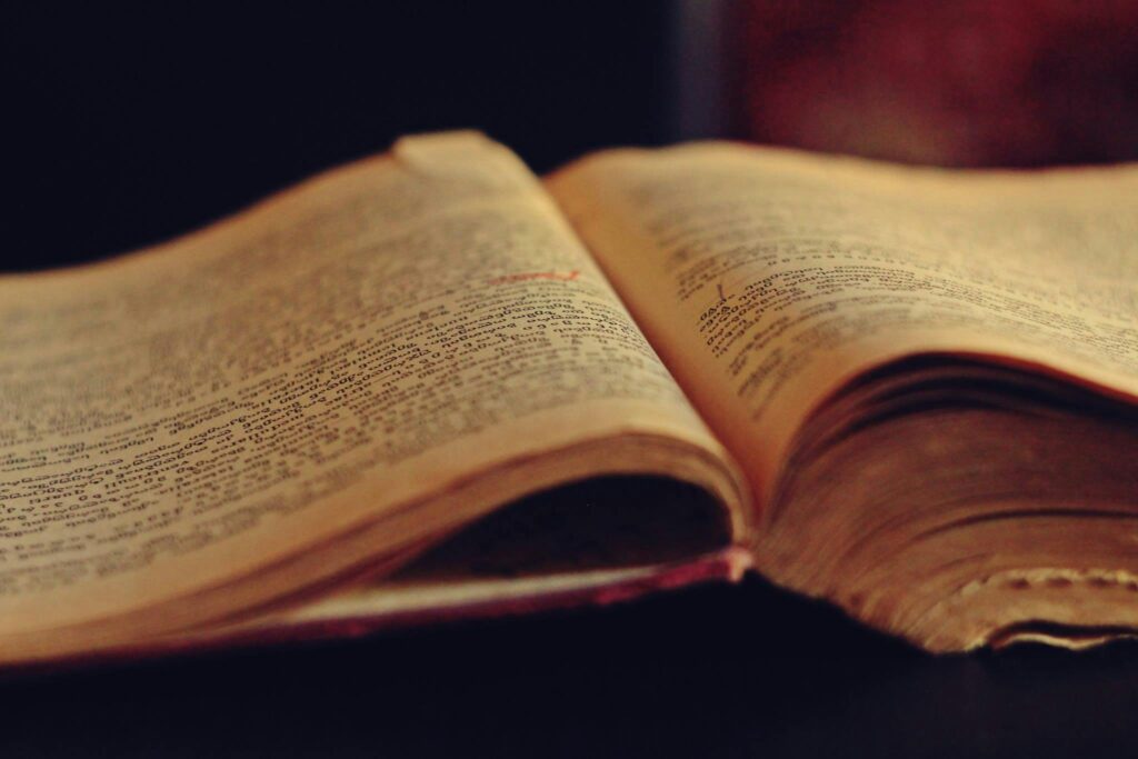 A vintage open book displaying aged, yellowed pages with faded text.